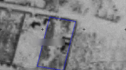 Historical black and white aerial photograph with the outline of a plot drawn in blue
