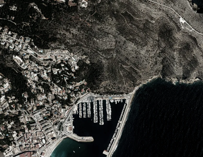 Ortofoto de la zona del puerto de Xàbia, con la ladera de monte, la costa acantilada y las casas junto al puerto