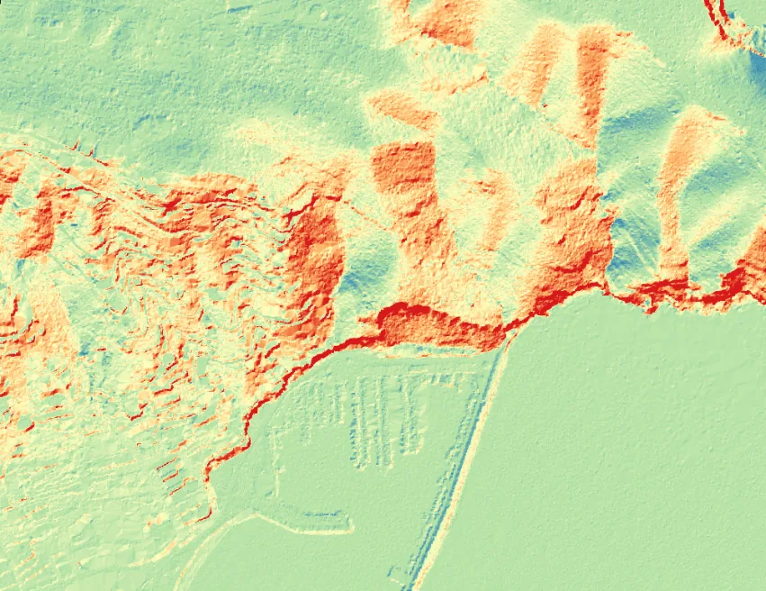 Mapa de pendientes de la misma zona por intervalos de color, de verde en las zonas llanas a rojo en las más inclinadas, con la costa acantilada en rojo intenso