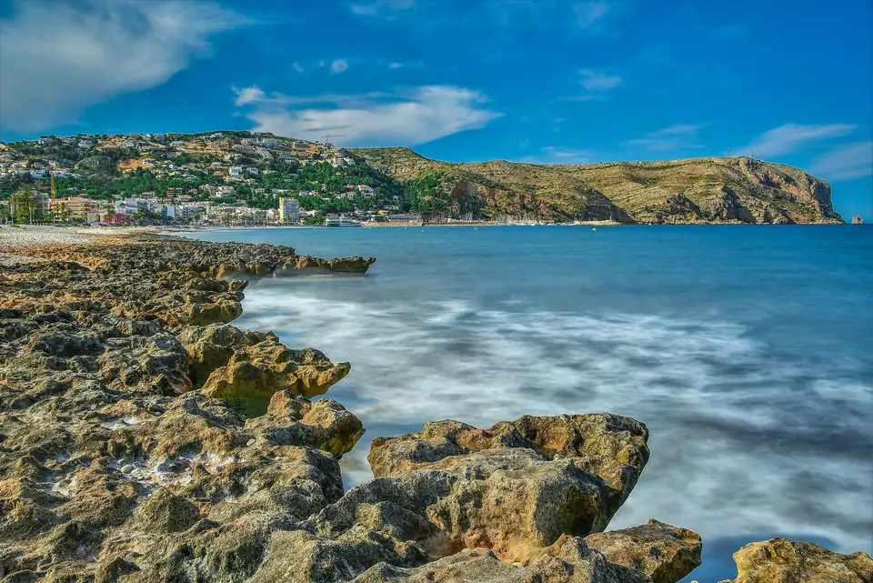 Costa rocosa de la Marina Alta con el pueblo y un cabo al fondo